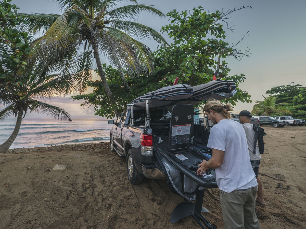Riders setting up an eFoil from a truck at a beach in Puerto Rico.